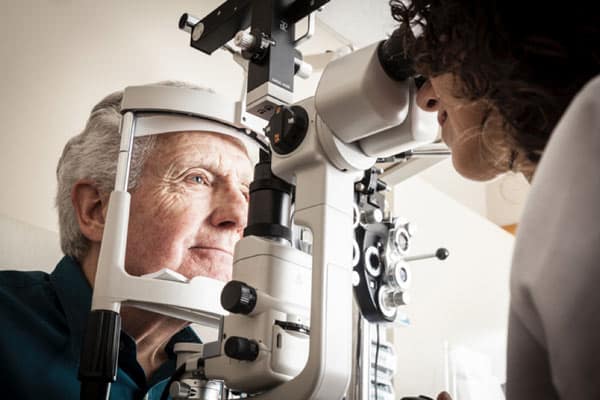 An older man sits for an eye exam, a crucial step in caring for aging eyes.